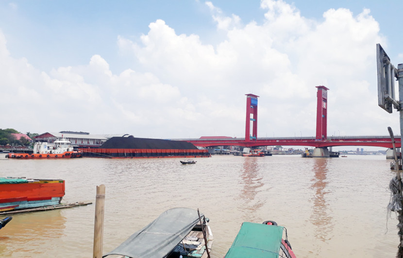 Angkutan batu bara menggunakan kapal tongkang melalui sungai Musi melintas di bawah jembatan Ampera landmark Kota Palembang. (FOTO: Maspril Aries)