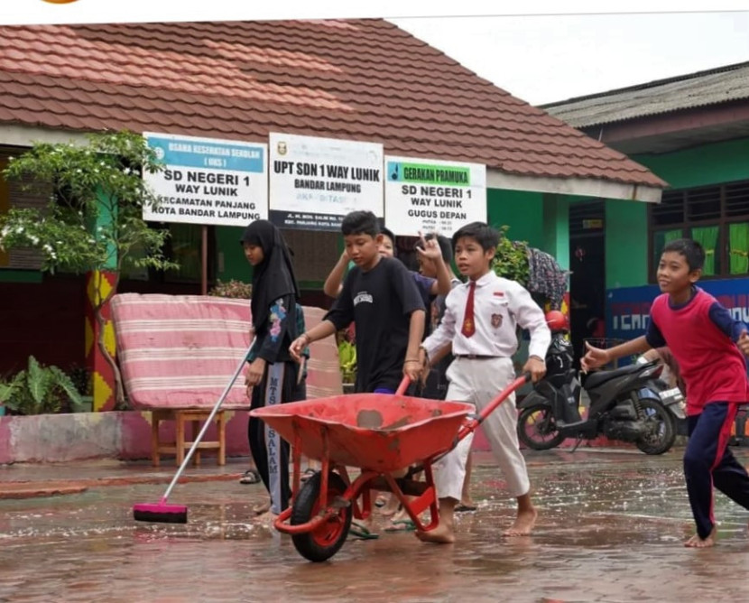 Anak-anak sekolah bergotong royong membersihkan sisa-sisa lumpur akibat banjir bandang, Senin (20/1/2025). (Foto: Dok. Diskominfotik Lampung)