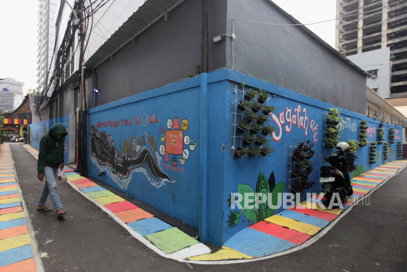 Warga berjalan di dekat mural di Gang 2, Kebon Sirih, Jakarta, Selasa (28/5/2024). Foto: Republika/Putra M. Akbar