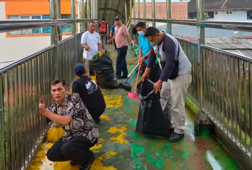 Petugas Dishub Kota Depok sedang membersihkan kotoran dan sampah di JPO Margonda. (Foto: Dok Diskominfo Kota Depok)