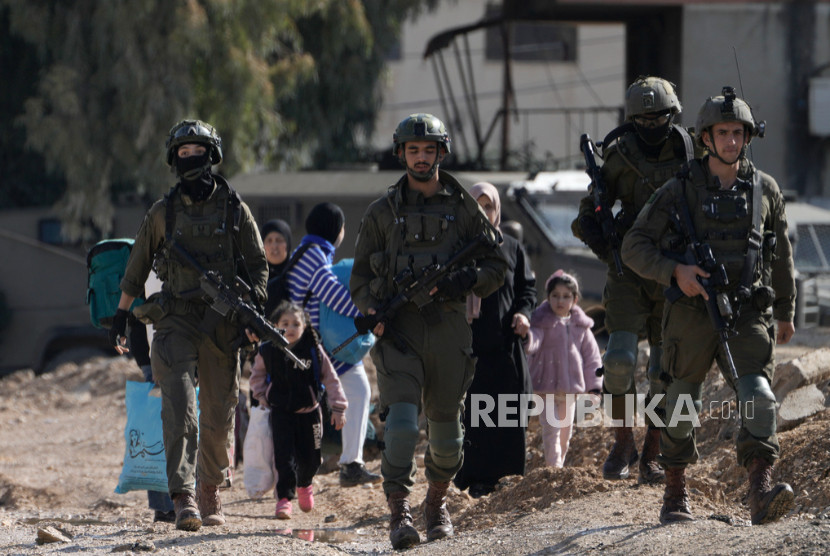 Tentara Zionis berjalan di tengah para pengungsi Palestina. 