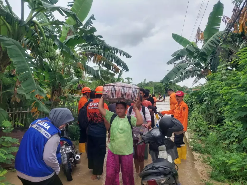 Personil BPBD Kabupaten Karawang melakukan evakuasi warga terdampak banjir pada Selasa 4/3/2025.