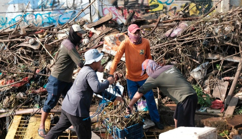 Petugas Dinas PUPR Kota Depok sedang mengangkat tumpukan sampah yang menyumbat sodetan di Situ Pengarengan, sehingga menyebabkan banjir di Perumahan Taman Duta. (Foto: Dok Diskominfo Kota Depok) 