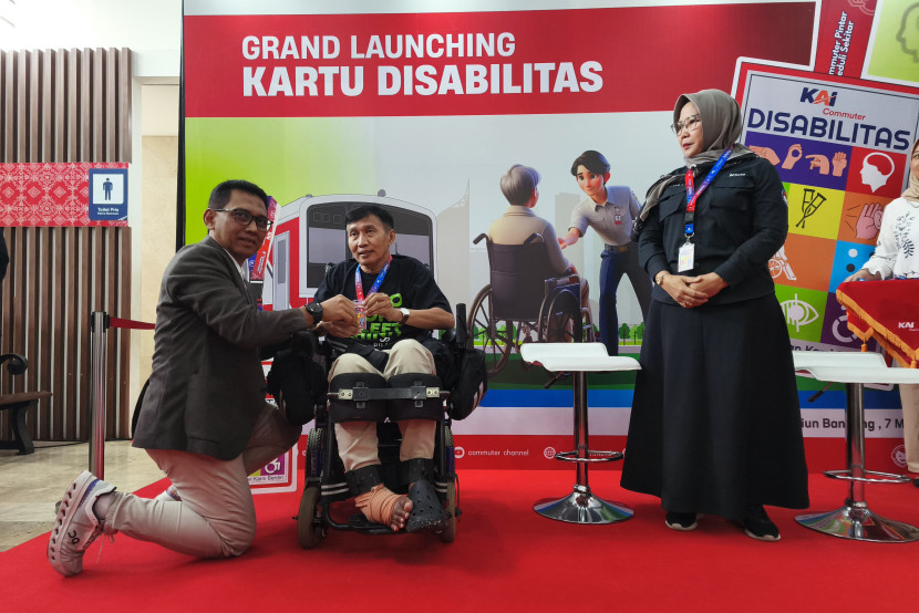 Direktur Utama KAI Commuter, Asdo Artriviyanto, mengalungkan fasilitas Kartu Disabilitas kepada Presiden Pergerakan Disabilitas dan Lanjut Usia (DILANS) Indonesia Farhan Helmy disaksikan Ketua Komisi Disabilitas Nasional (KDN) Dante Rigmalia di Stasiun Bandung, Jumat (7/3/2025).