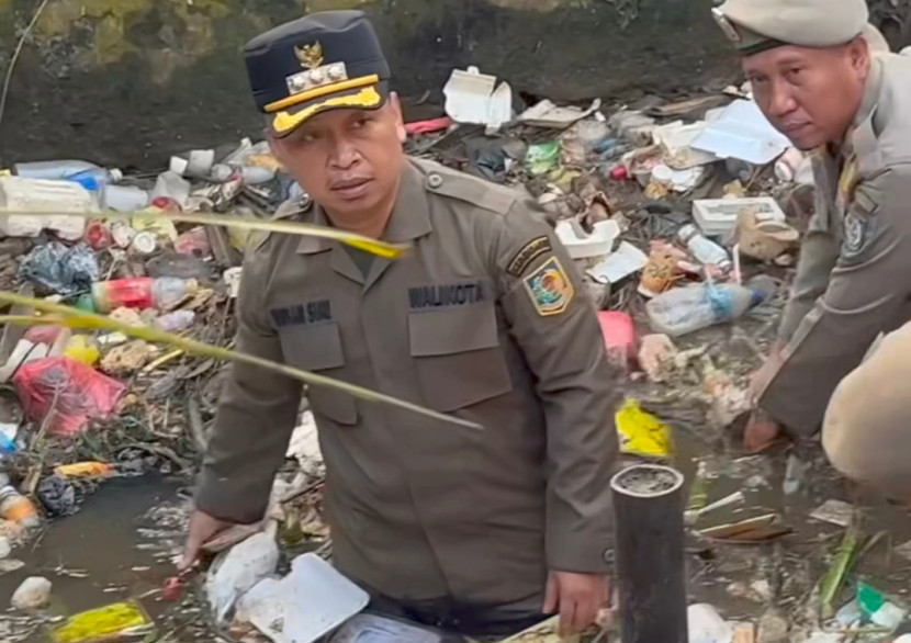 Wali Kota Depok, Supian Suri terjun langsung membersihkan sampah yang menumpuk dan menyumbat aliran air di Kali Cabang Tengah (KCT) di Balai Kota Depok. (Foto: Dok RUZKA INDONESIA) 