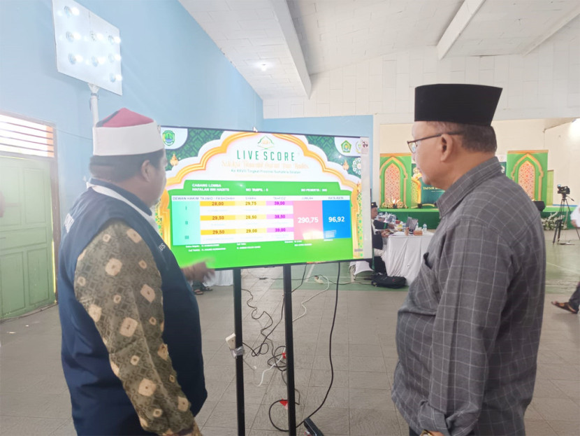 Iklim Cahya (kanan) memerika tayangan live score di layar (FOTO: Dok. LPTQ Sumsel)