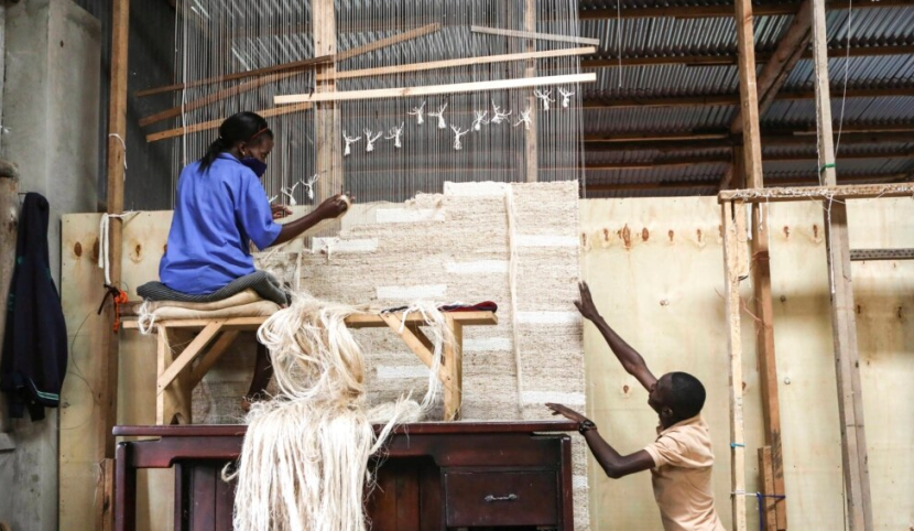 Menganyam karpet menggunakan benang serat pisang, di pabrik Texfad di Sonde, Distrik Mukono, Uganda/AP/Hajarah Nalwadda