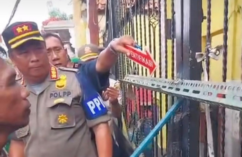 Aparat Satpol PP Kota Depok dibantu kepolisian Polrestro Depok membuka pintu gerbang yang digebok oleh warga yang mengaku ahli waris SDN Utan Jaya. (Foto: Dok RUZKA INDONESIA)