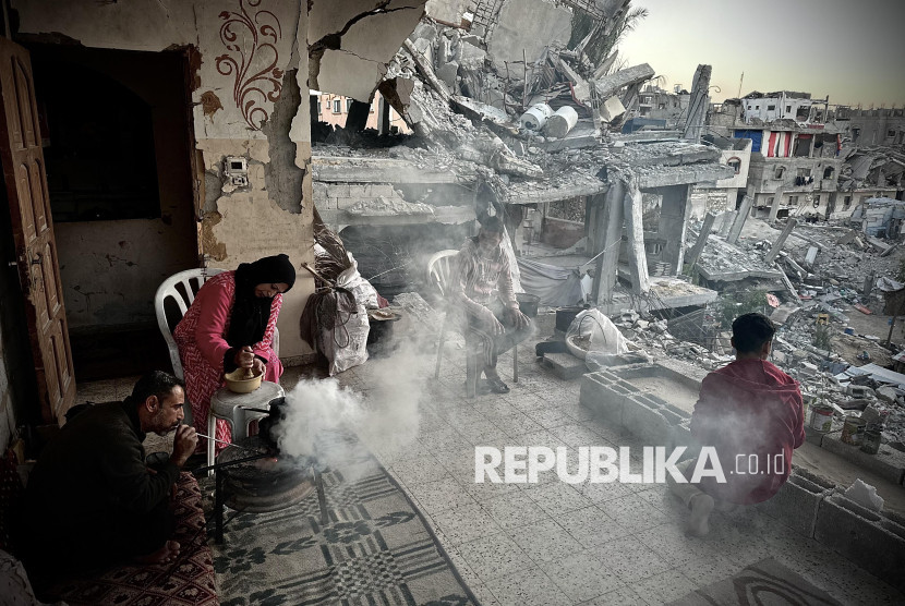 Keluarga Palestina, di tengah reruntuhan bangunan akibat genosida.