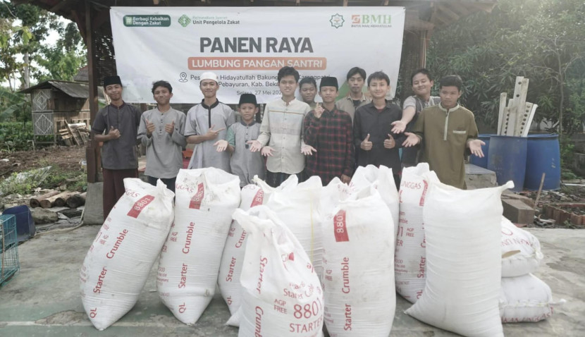 Para santri berfoto bersama dengan hasil panen padi organik.