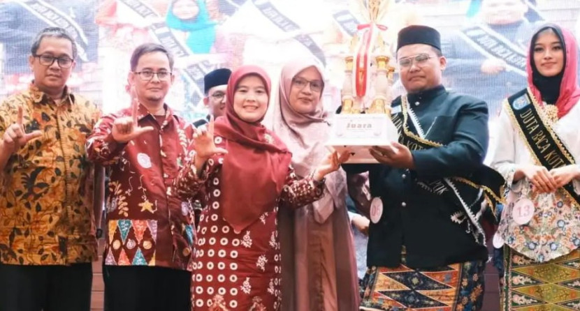 Ketua TP-PKK Kota Depok, Siti Barkah Hasanah memberikan piala kepada juara pertama Duta Baca Kota Depok Tahun 2025 yang dihelat di Balai Kota Depok, Sabtu (14/06/2025). (Foto: Diskominfo Kota Depok).