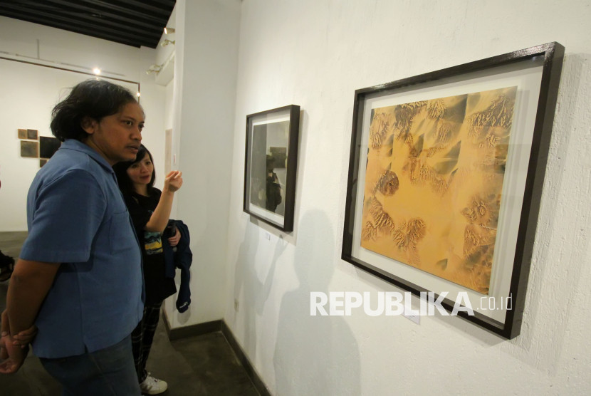 Pengunjung melihat karya seni rupa bertajuk 'Purnama (dan) Tilem' karya Iswanto Soerjanto yang dipamerkan di Orbital Dago Gallery, Kota Bandung. Foto: Edi Yusuf