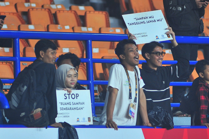 Aktivis volunter kebersihan membawa  plakat himbauan di tribun penonton di sela laga Piala Presiden 2025 di Stadion si Jalak Harupat, Kabupaten Bandung. KANGJEPRET/YOGIARDHI (Data teknis: Nikon D3, Nikkor 300/2.8 ED Manual Focus)