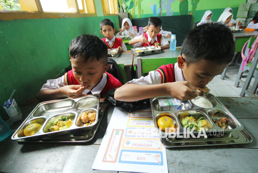 Para siswa menikmati Makanan Bergizi Gratis (MBG) saat kegiatan Masa Pengenalan Lingkungan Sekolah (MPLS) dan peluncurkan program MBG di SDN 158 Babakan Sari Babakan Surabaya, Senin (14/7/2025). Foto: Edi Yusuf
