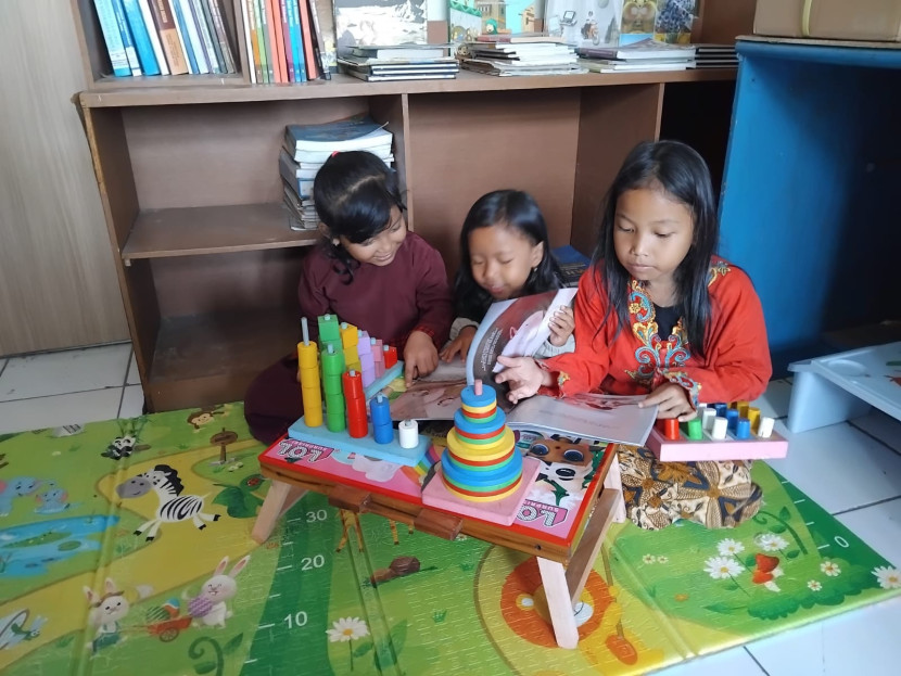 Anak-anak tengah membaxa buku sambil bermain di Perpustakaan Kelurahan Tipar, Kecamatan Citamiang, Kota Sukabumi, Kamis (17/7/2025).