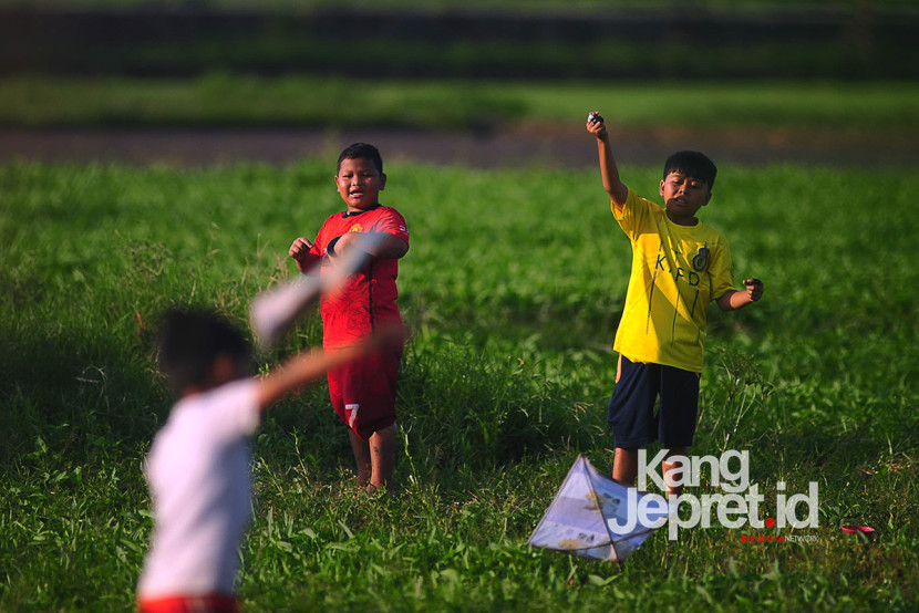 Sejumlah anak bermain layang-layang di lahan kebun kangkung yang mengering Lingkung Cai Kel Kujangsari, Bandung Kidul, Kamis (31/7/2025). Kangjepret/Yogi Ardhi (Data Teknis Nikon D3, Nikkor MF 300mm f/2.8).