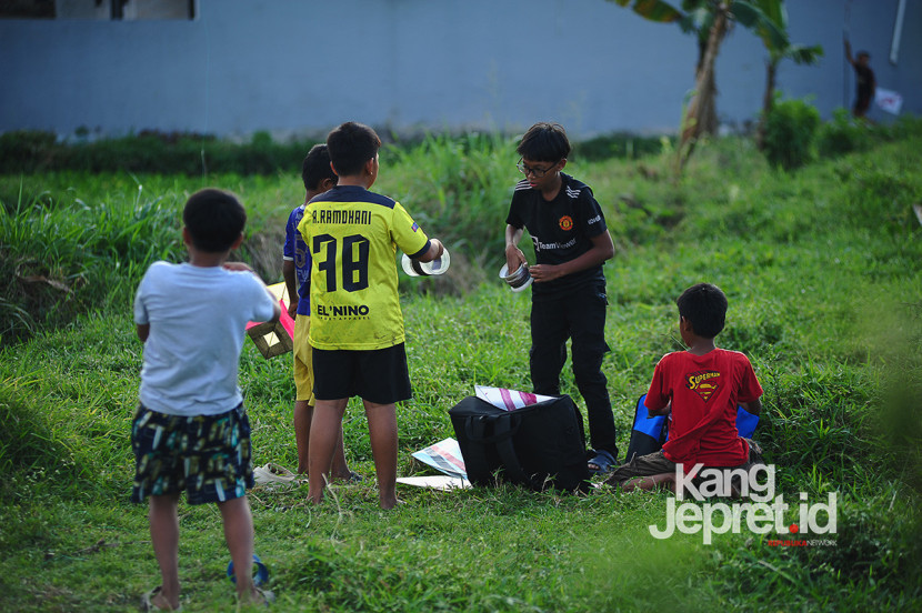 Sejumlah anak menyiapkan benang sebelum menerbangkan layang-layang di tanah lapang Lingkung Cai Kel Kujangsari, Bandung Kidul, Kamis (31/7/2025). Kangjepret/Yogi Ardhi (Data Teknis Nikon D3, Nikkor Nikkor AF 80-200mm f/2.8 ED 3rd gen).