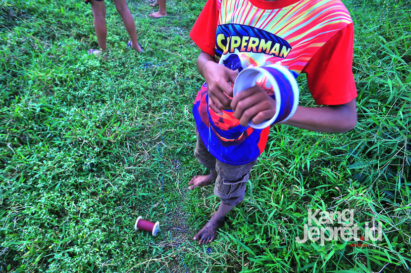 Seorang anak menggulung benang gelasan sebelum menerbangkan layang-layang di tanah lapang Lingkung Cai Kel Kujangsari, Bandung Kidul, Kamis (31/7/2025). Kangjepret/Yogi Ardhi (Data Teknis Nikon D3, Nikkor AF 20mm f/2.8 D).