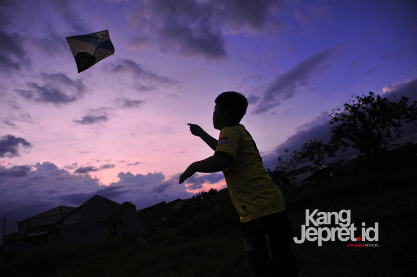 Seorang anak menerbangkan layang-layang menjelang senja di tanah lapang Lingkung Cai Kel Kujangsari, Bandung Kidul, Kamis (31/7/2025). Kangjepret/Yogi Ardhi (Data Teknis Nikon D3, Nikkor AF 20mm f/2.8 D).