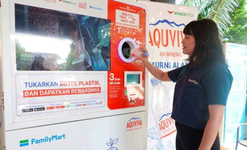 Business Development FamilyMart, Kartika Pangestu, sedang Menunjukkan Penukaran Botol Plastik PET ke Dalam Mesin RVM AQUVIVA. (Foto: Dok. WINGS Food) 