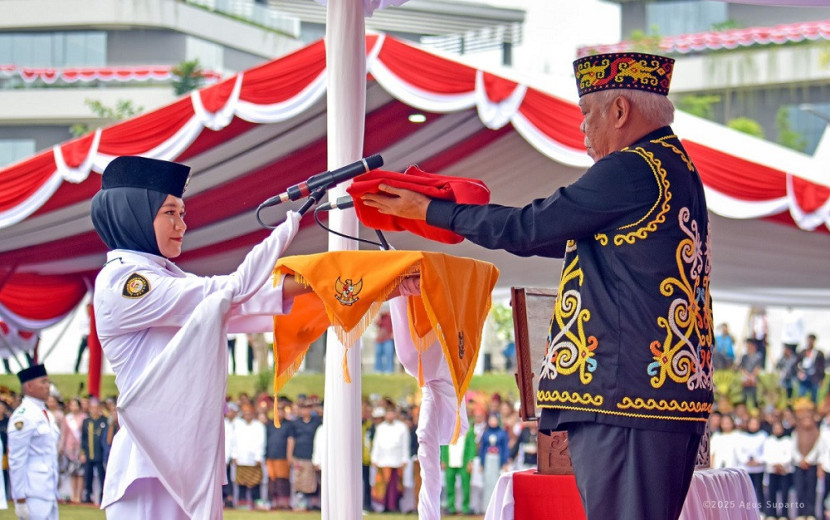 Kepala OIKN Basuki Hadimuljono menyerahkan bendera Merah Putih kepada pembawa baki, Aulia Novita, siswi SMAN 2 Penajam Paser Utara, Kalimantan Timur. (OIKN)