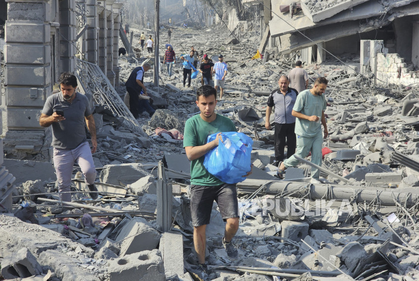 Warga Gaza melewati reruntuhan bangunan yang dihancurkan penjajah zionis.