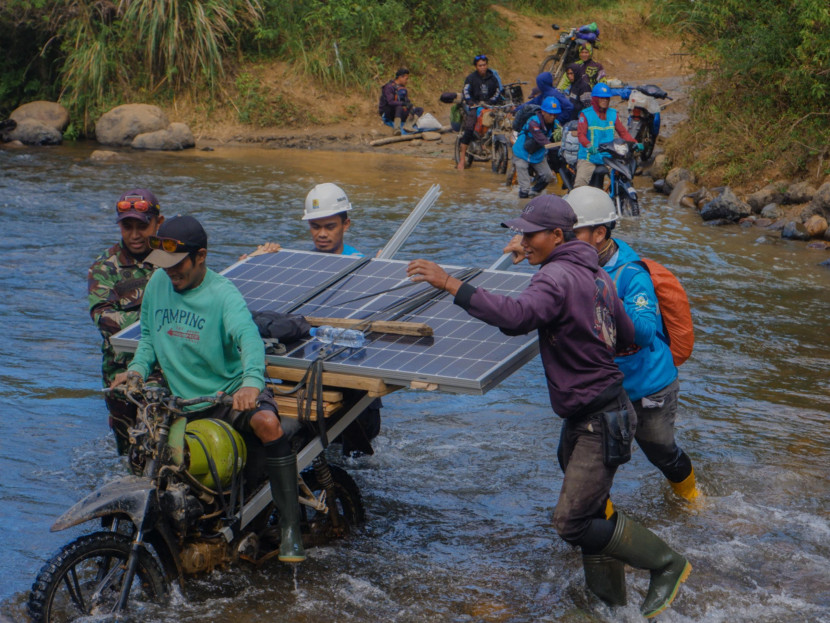 Petugas PLN bersama warga bahu-membahu membawa panel surya melintasi sungai. Upaya ini menjadi bagian dari perjalanan Program Listrik Desa (Lisdes) melalui SuperSUN dalam menghadirkan akses listrik bagi warga di Kecamatan Seko, Luwu Utara, Sulawesi Selatan. (Foto: Dok Ruzka Indonesia/PLN) 
