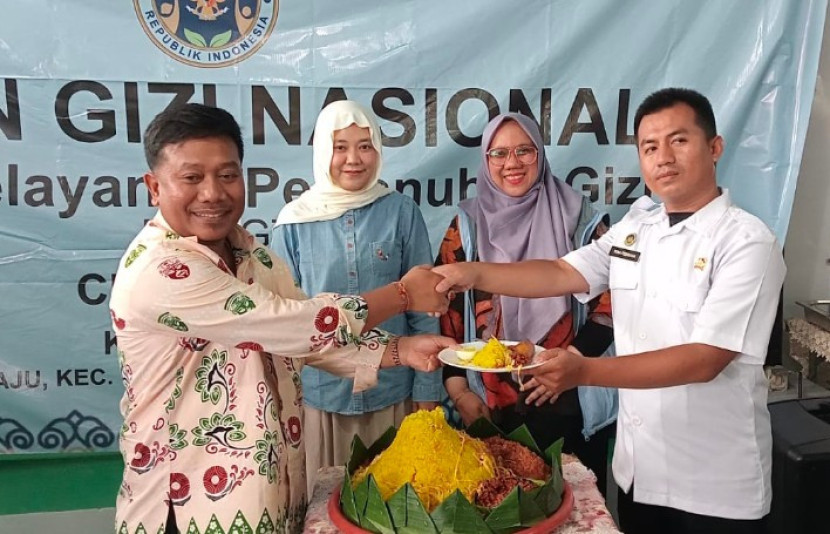 Camat Cilodong, Zainal Arifin (kiri) memotong tumpeng menandai peresmian dapur MBG Yayasan Berkah Siti Asmah. (Foto: Dwi Retno)