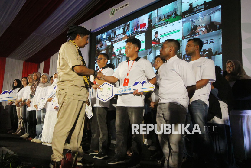 Meteri PKP Maruarar Sirait secara simbolis menyerahkan kunci saat akad massal dan serah terima kunci 1.080 debitur FLPP Bank BJB dan BJB Syariah, di Aula Kahatex, Jalan Rancaekek, Kabupaten Sumedang, Jumat (22/8/2025). Foto: Edi Yusuf
