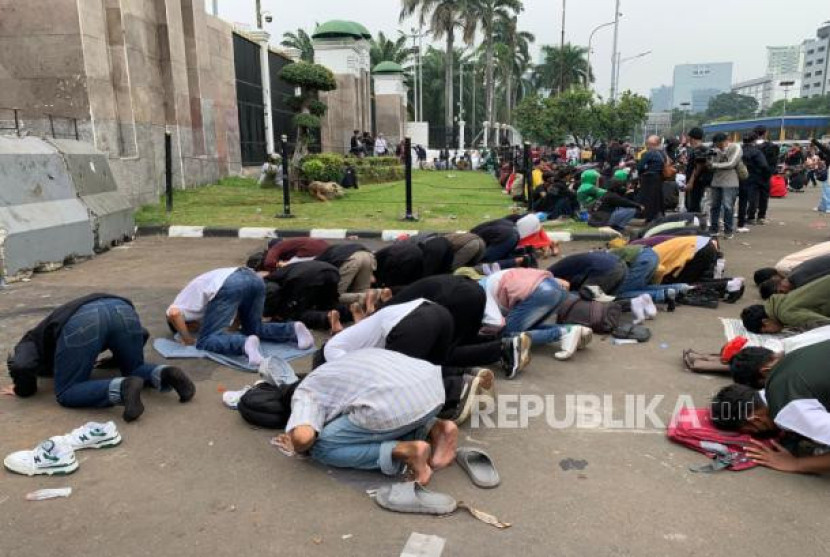 Sejumlah massa menyempatkan diri untuk shalat Dzuhur di depan gedung DPR RI.