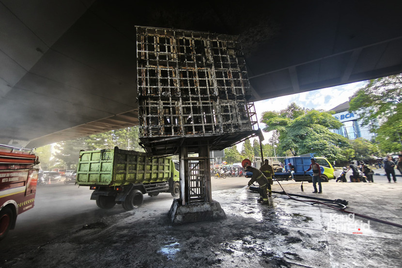 Petugas dinas kebersihan dan penanggulangan kebakaran membersihkan sisa videotron yang hangur terbakar di Jalan Dago, Bandung, Sabtu (30/8/2025). Aksi demo massa sehari sebelumnya membakar berbagai benda di gerbang gedung wakil rakyat ini. (KANGJEPRET.ID/YOGI ARDHI) (Kamera: Xiaomi 14T). 