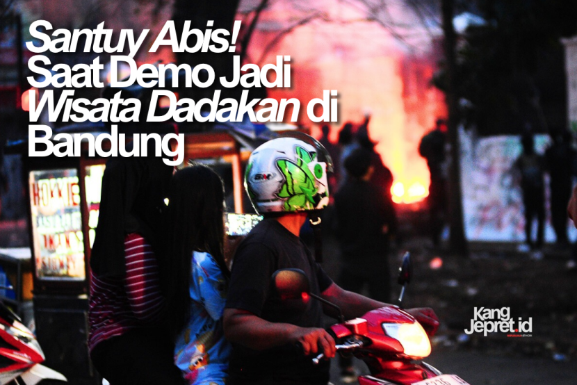 Tiga orang warga berboncengan di atas motor menonton aksi pembakaran oleh pengunjukrasa di gerbang Gedung DPRD Jawa Barat, Jl Diponegoro, Bandung, Senin (1/9/2025). Aksi unjukrasa beberapa hari berubah menjadi tontonan warga dan pedagang yang mencari peruntungan di keramaian massa. (KANGJEPRET.ID/YOGI ARDHI) (Nikon D700, Nikkor 80-200/2.8 ED 3rd Gen)