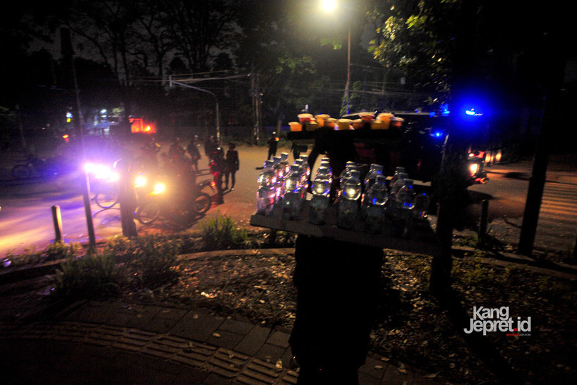 Seorang pedagang minuman masih berjualan setelah aparat polisi membubarkan massa pengunjukrasa usai magrib di area Gedung DPRD Jawa Barat, Jl Diponegoro, Bandung, Senin (1/9/2025). Menurut aturan yang berlaku, pelaksanaan unjukrsasa dibatasi hingga pukul 18.00. Aksi unjukrasa beberapa hari berubah menjadi tontonan warga dan pedagang yang mencari peruntungan di keramaian massa. (KANGJEPRET.ID/YOGI ARDHI) (Nikon D3, Nikkor 20/2.8 D)