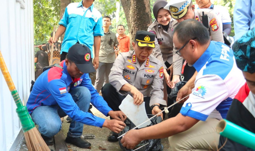 Ketua Buruh Kota Depok, Wido Pratikno (kiri) bersama Kapolres Depok, Kombes Abdul Waras lakukan aksi damai dan bersih-bersih Pos Lantas yang sempat dirusak massa. (Foto: Humas Polres Depok)