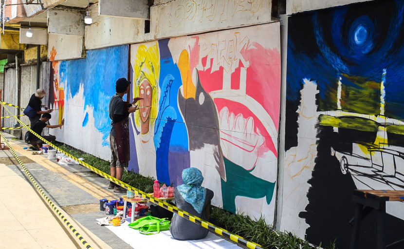 Pelukis Palembang tengah melukis mural. (FOTO: Ist/Msh)