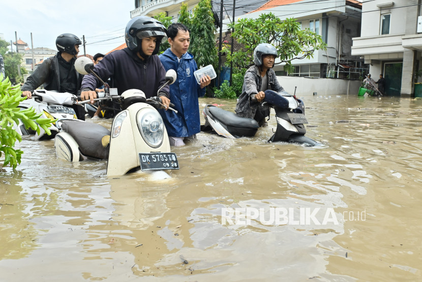 Warga mendorong sepeda motor melewati banjir yang menggenangi kawasan Kuta, Badung, Bali, Rabu (10/9/2025). Hujan yang mengguyur wilayah Bali sejak Selasa (9/9) mengakibatkan banjir di berbagai titik dengan ketinggian air yang bervariasi hingga mencapai 1,5 meter. (Dok Antara Foto)
