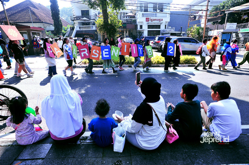 Arak-arakan Tapak Meriah melintasi area Car Free Day (CFD) di Jl Dago, Bandung, Ahad (21/9/2025). Warga menonton aksi seni yang menandai penyelenggaraan Pasar Seni ITB 2025 pada Oktober mendatang. (KANGJEPRET.ID/ YOGI ARDHI) (Nikon D3, Nikkor AF 20/2.8 D)