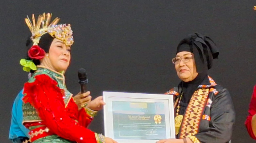 Maestro Tari Betawi Wiwiek Widiyastuti (kanan) menerima Apresiasi Budaya dari Ketua Umum Bakul Budaya FIB UI, Dewi Fajar Marhaeni, dalam perayaan HUT ke-3 Bakul Budaya FIB UI dan Hari Tenun Nasional 2025 di Auditorium Soe Hok-gie, Gedung IX FIB UI, pada 21 September 2025. (Foto: Dok Bakul Budaya) 