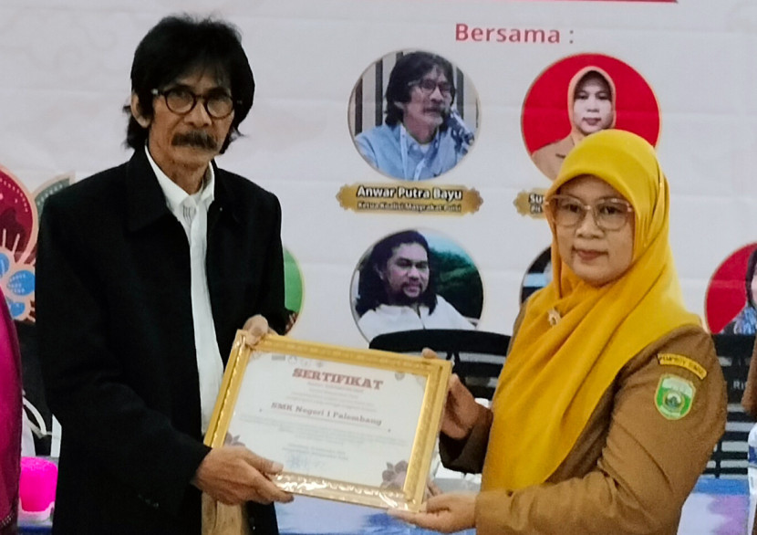 Ketua Koalisi Masyarakat Puisi Anwar Putra Bayu (kiri) menyerahkan sertifikat kepada Wakil Kepala SMKN 1 Palembang. (FOTO: Maspril Aries)