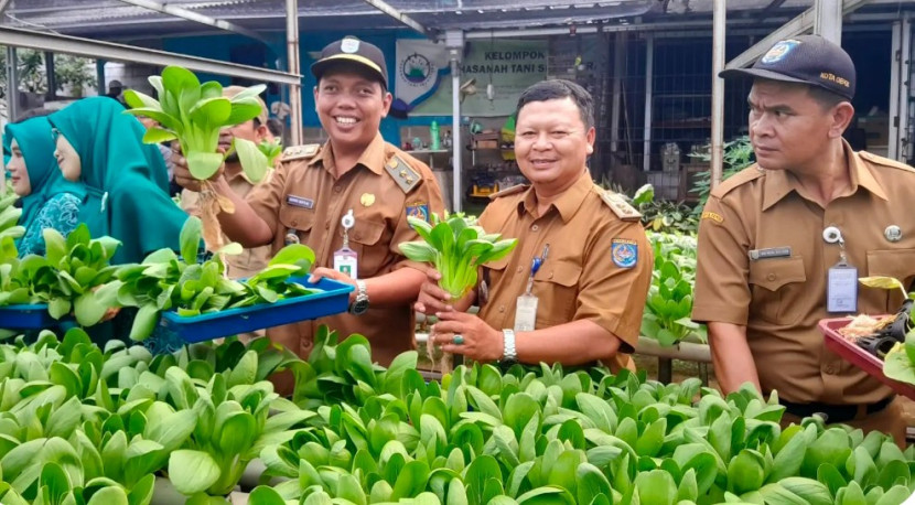 Lurah Curug, Ahmad Sofyan (kiri) saat panen raya Sekolah Rakyat Agribisnis (Sera Agribisnis) yang berlokasi di RW 02, Kelurahan Curug, Kecamatan Bojongsari, Kota Depok, Senin (13/10/2025). (Foto: Diskominfo Kota Depok)