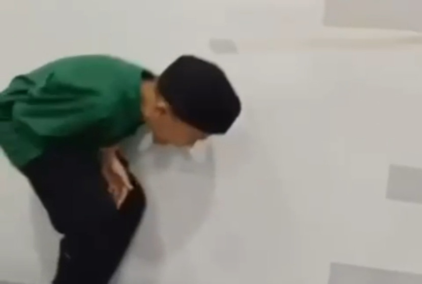Seorang santri GISBH tertunduk menahan sakit akibat kekerasan fisik yang dialaminya. Gambar diambil dari sreenshot video yang beredar.