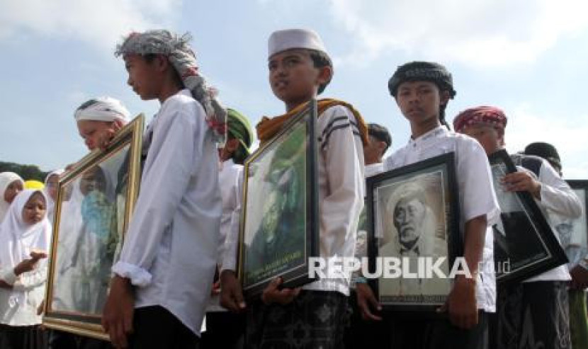 Santri membawa foto sejumlah kyai saat mengikuti gerak jalan dalam Festival 1001 Terompah di Lapangan Tumapel, Singosari, Malang, Jawa Timur, Rabu (22/10/2025). Festival yang digelar untuk memeriahkan Hari Santri Nasional 2025 itu juga diisi dengan gerak jalan berterompah sebagai simbol kesederhanaan dan penguatan nilai-nilai keislaman di kalangan santri. (FOTO : ANTARA/Ari Bowo Sucipto)
