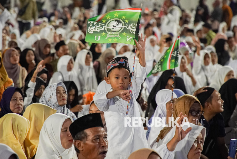 Anak mengibarkan bendera sembari melantunkan selawat saat peringatan Hari Santri di Stadion Semeru, Lumajang, Jawa Timur, Sabtu (18/10/2025). Gelaran selawat dan doa bersama yang diikuti ribuan santri serta masyarakat sekitar itu digelar dalam rangka memperingati Hari Santri Nasional yang jatuh pada 22 Oktober. (FOTO: ANTARA /Irfan Sumanjaya)