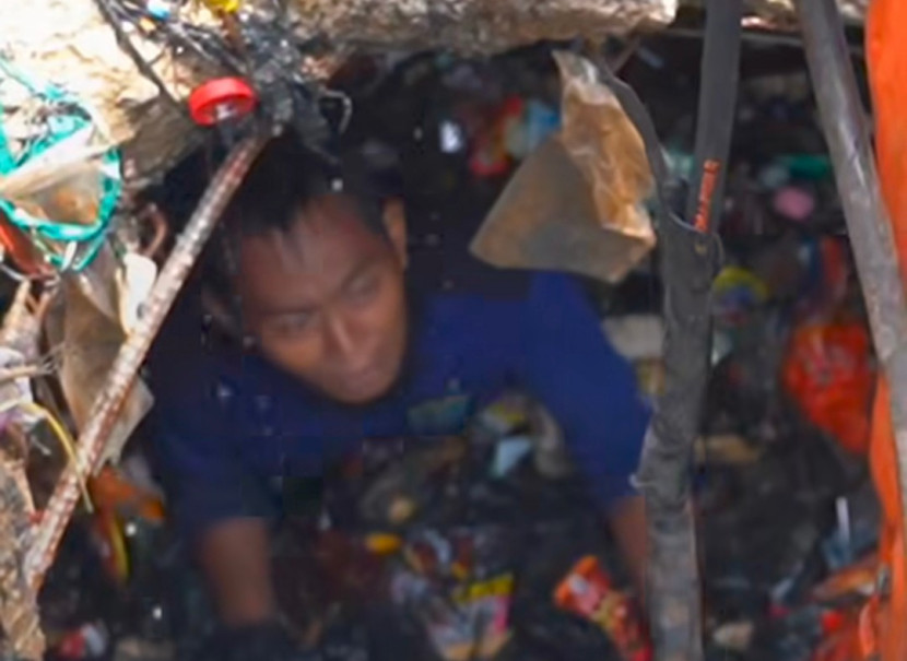 Seorang petugas Satgas Banjir Dinas PUPR Kota Depok masuk ke gorong-gorong mengangkat sampah yang menumpuk di Kali Cabang Tengah di depan Detos, Kamis (23/10/2025). Tumpukan sampah yang menghambat aliran air menyebabkan Jalan Margonda Raya kerap banjir saat hujan. (Foto: Dok RUZKA INDONESIA)