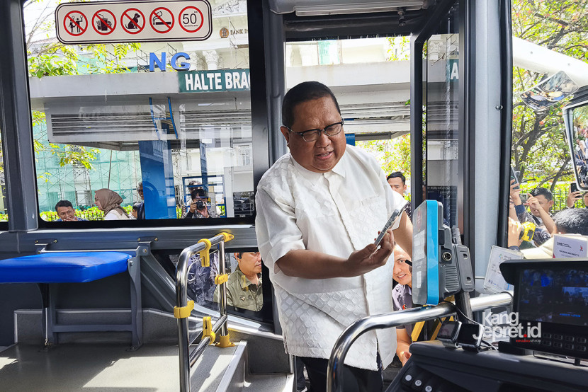 Kepala Perwakilan BI Provinsi Jabar, Muhamad Nur menyentuhkan gawai ke alat pemindai NFC pembayaran saat menaiki Metro Trans Jabar  pada acara peresmian QRIS Tap dan feeder Metro Trans Jabar di Halte Bank Indonesia Perwakilan Jabar, Bandung, Jumat (24/10/2025). KANGJEPRET/ YOGI ARDHI (Data kamera: Xiaomi 14 T, 23mm lens)