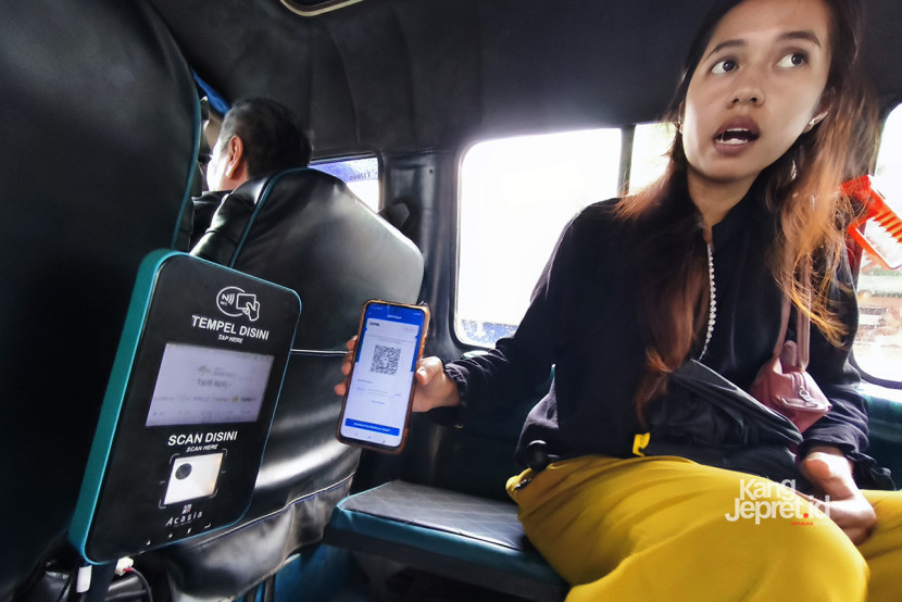 Seorang penumpang memindai kode QRIS saat melakukan pembayaran di angkot Feeder MJT di Bandung, Jumat (31/10/2025). Selain QRIS konvensional unit pemindai yang sama juga bisa digunakan untuk QRIS Tap dan kartu dompet digital berbagai bank. KANGJEPRET.ID/ YOGI ARDHI (Data: Nikon D700, Nikkor 20/2.8 D)