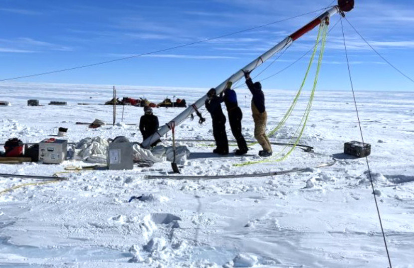 Para peneliti mengangkat bor yang mereka gunakan untuk menggali inti. (Julia Marks Peterson/COLDEX)