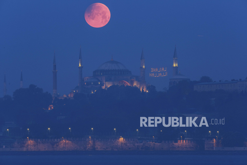 Bulan purnama muncul di atas Haghia Sophia yang ikonik di Istanbul, Turki, Senin pagi, 16 Mei 2022.