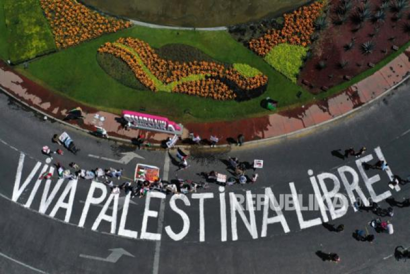 Peserta aksi menulis grafiti 'Hidup Palestina Merdeka' di jalan raya dalam aksi unjuk rasa solidaritas untuk rakyat Palestina di Kota Guadalajara, Meksiko, Senin (23/10/2023). (dok. EPA-EFE/Francisco Guasco)
