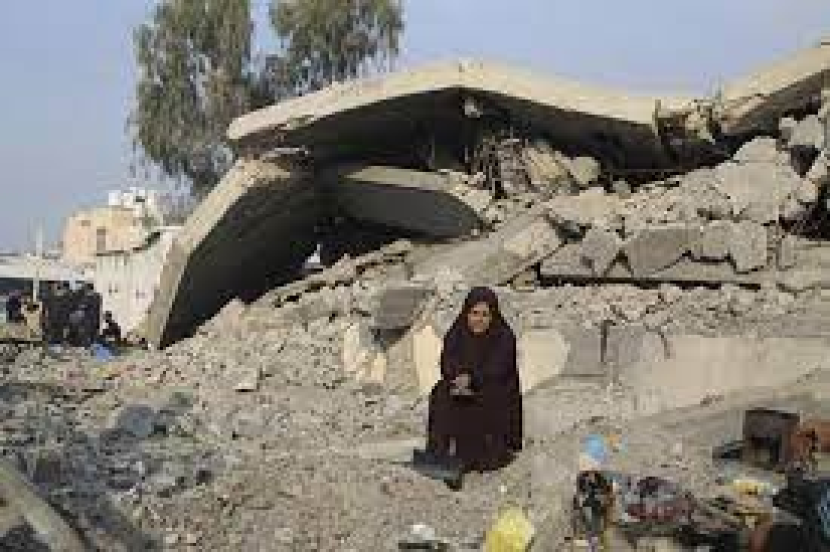 Perempuan Palestina terduduk menangis di depan  pemukimannya yang hancur.